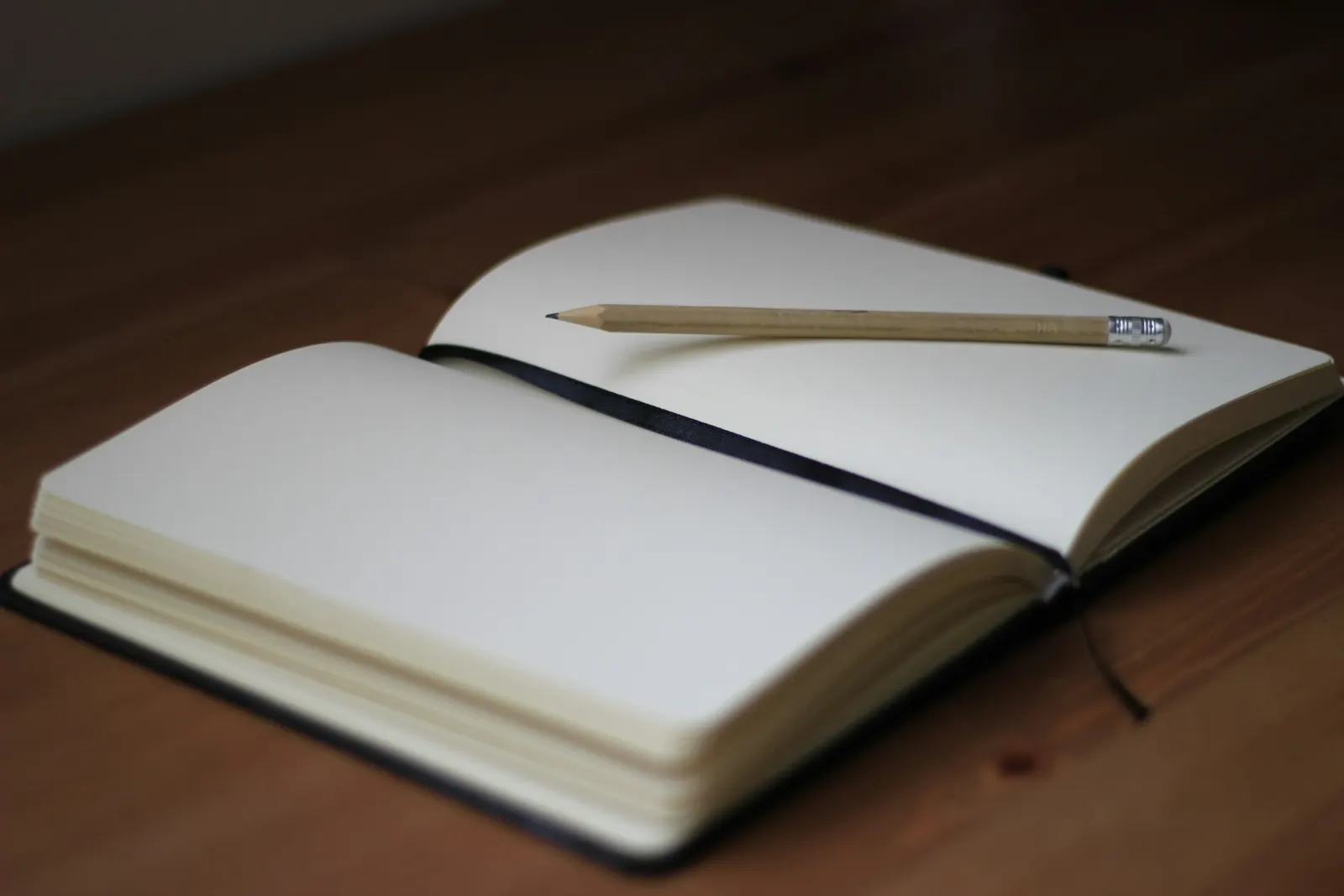 An open notebook and a pencil on a wooden table